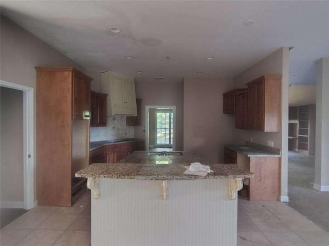 164 Mcclain Cir, Macon, GA 31216 - kitchen with a kitchen island, light stone countertops, a kitchen bar, and brown cabinetry
