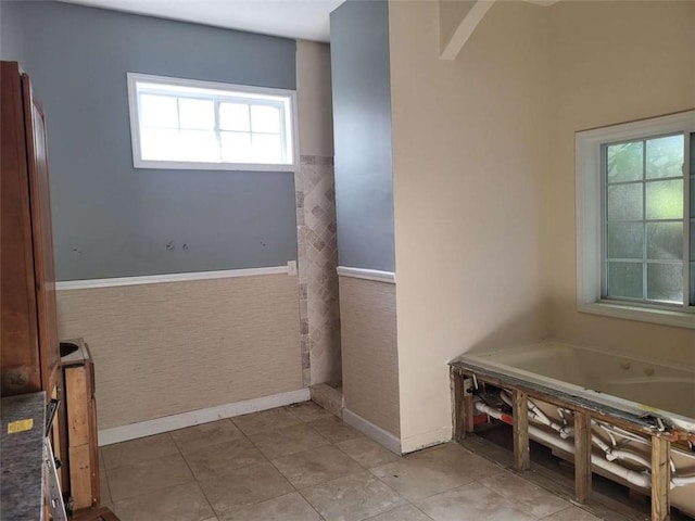 164 Mcclain Cir, Macon, GA 31216 - bathroom featuring a garden tub, a wainscoted wall, and tile patterned floors