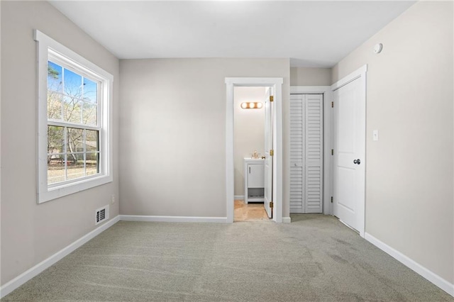 unfurnished bedroom featuring light carpet and connected bathroom