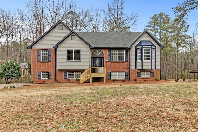 raised ranch featuring brick siding and a front lawn