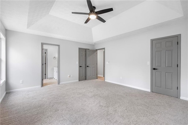 unfurnished bedroom with carpet, baseboards, and a raised ceiling