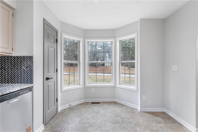 unfurnished dining area with a textured ceiling, visible vents, and baseboards