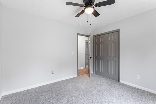 unfurnished bedroom featuring ceiling fan, a closet, carpet flooring, and baseboards