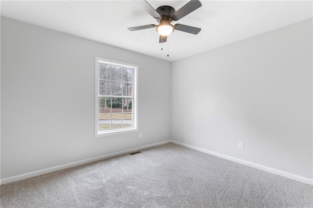 carpeted empty room featuring ceiling fan, a textured ceiling, visible vents, and baseboards