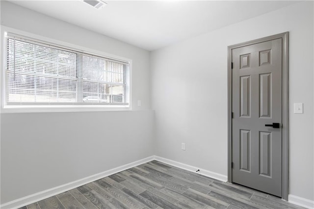 spare room with wood finished floors, visible vents, and baseboards