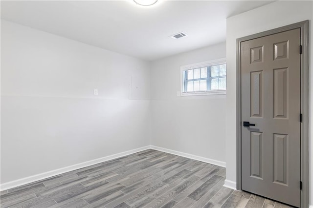 unfurnished room featuring wood finished floors, visible vents, and baseboards