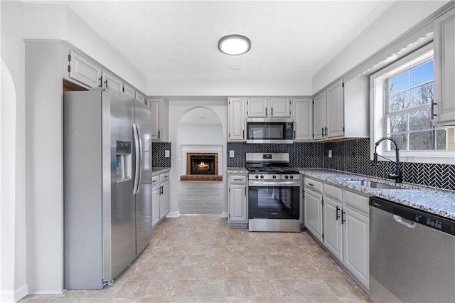 kitchen with decorative backsplash, appliances with stainless steel finishes, gray cabinets, and a sink