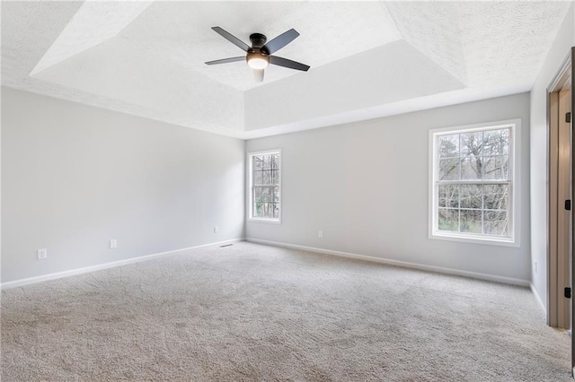 carpeted empty room featuring baseboards, a raised ceiling, and a textured ceiling