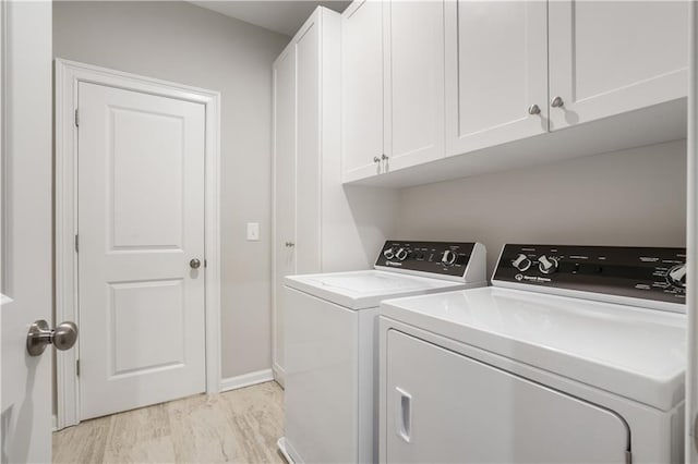 clothes washing area with cabinets, washer and dryer, and light wood-type flooring