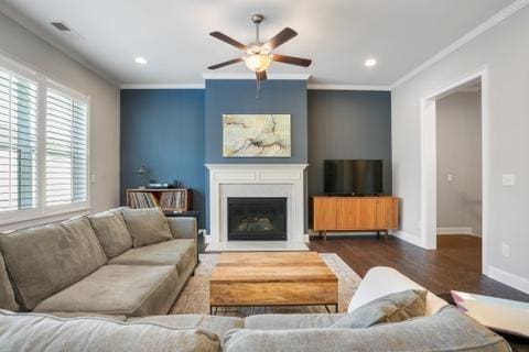 living room with ornamental molding, dark hardwood / wood-style floors, and ceiling fan