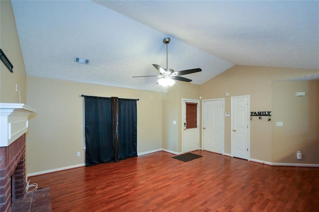 unfurnished living room featuring ceiling fan, vaulted ceiling, dark hardwood / wood-style floors, and a brick fireplace