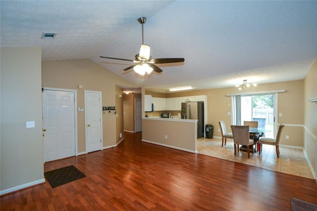 living room with hardwood / wood-style floors, ceiling fan with notable chandelier, lofted ceiling, and a textured ceiling