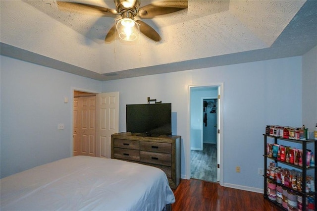 bedroom with a textured ceiling, dark hardwood / wood-style flooring, ceiling fan, and a closet