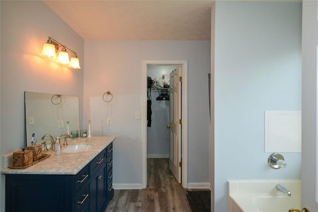 bathroom featuring vanity, a tub, hardwood / wood-style flooring, and a textured ceiling