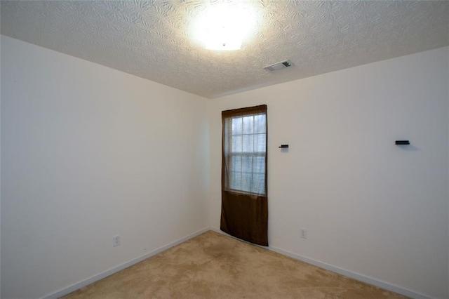 unfurnished room featuring a textured ceiling and light colored carpet