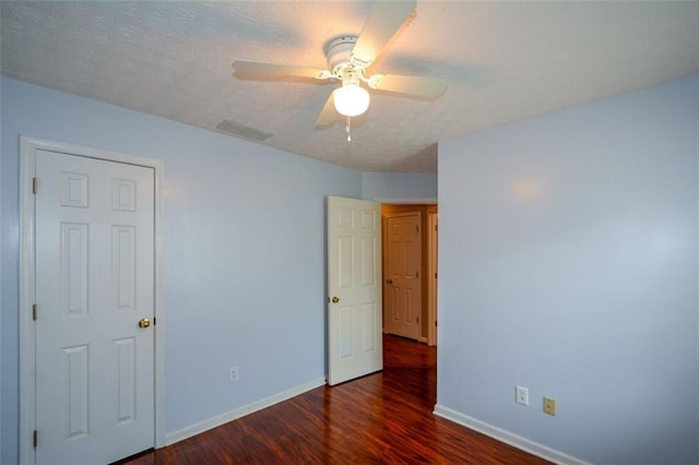 spare room with a textured ceiling, dark wood-type flooring, and ceiling fan