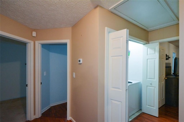 corridor featuring a textured ceiling, dark hardwood / wood-style floors, and washer / dryer