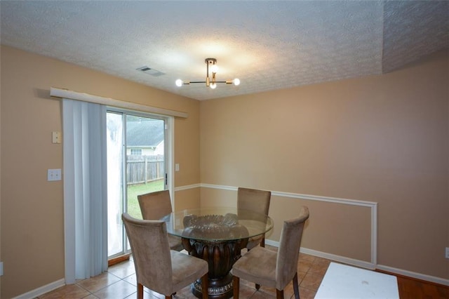 tiled dining room with a notable chandelier and a textured ceiling