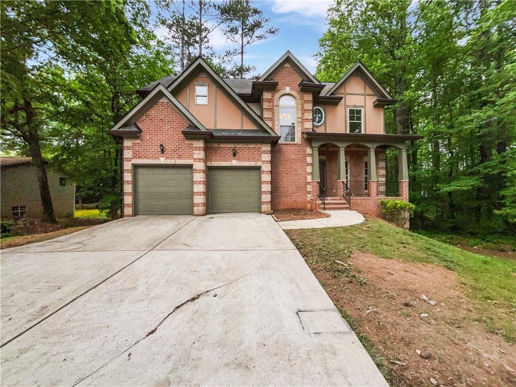 view of front of home with driveway, covered porch, brick siding, and stucco siding