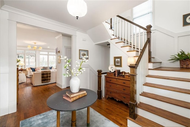 stairs featuring crown molding, hardwood / wood-style floors, and a chandelier