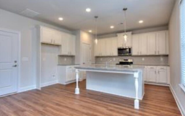 1091 Boulder Dr, Gray, GA 31032 - kitchen featuring stainless steel microwave, white cabinets, range, backsplash, and recessed lighting