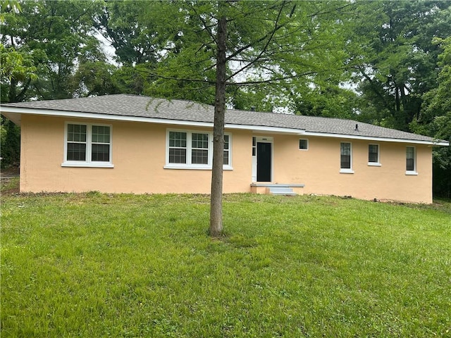 back of house featuring stucco siding, a yard, and view of scattered trees