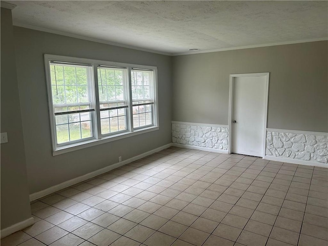 tiled spare room with a textured ceiling, crown molding, and baseboards