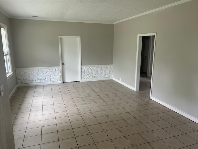 tiled spare room with crown molding and baseboards