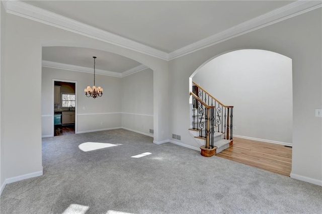 unfurnished room featuring carpet floors, ornamental molding, and a notable chandelier