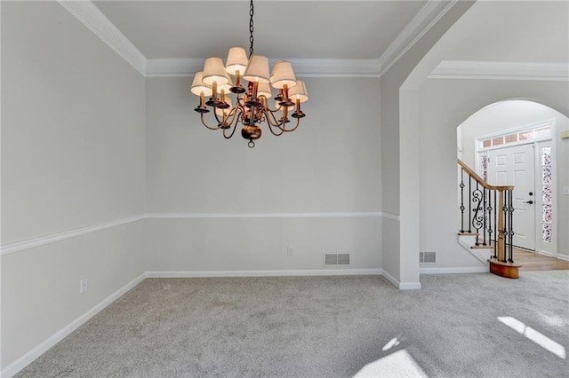 carpeted empty room featuring crown molding and a chandelier