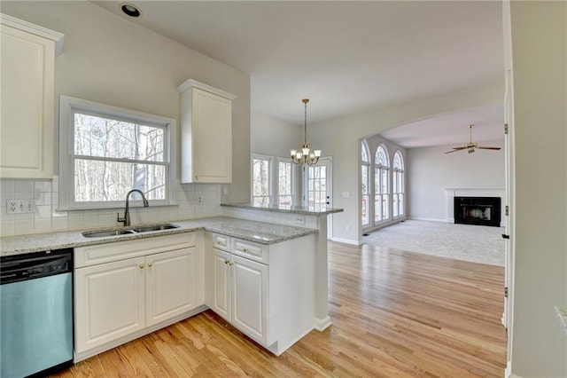 kitchen featuring dishwasher, a high end fireplace, kitchen peninsula, sink, and white cabinetry