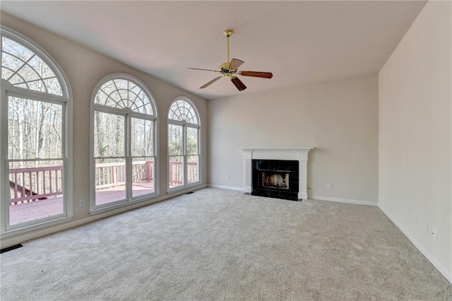 unfurnished living room featuring a fireplace, ceiling fan, and carpet