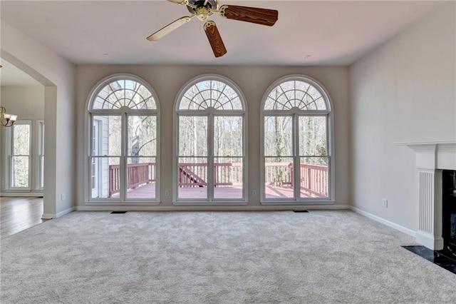 unfurnished living room with a wealth of natural light, light colored carpet, and a high end fireplace