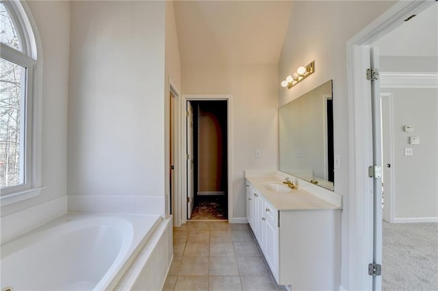 bathroom featuring lofted ceiling, vanity, tile patterned floors, and a relaxing tiled tub