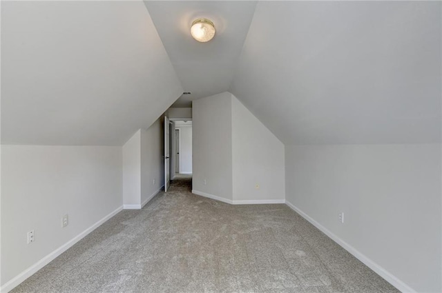 bonus room with light colored carpet and vaulted ceiling