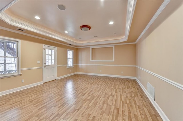 spare room featuring light wood-type flooring, a tray ceiling, and crown molding