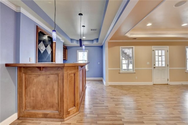 bar with decorative light fixtures, ornamental molding, a tray ceiling, and a wealth of natural light