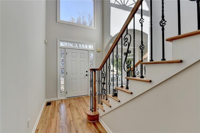 foyer with a towering ceiling, plenty of natural light, and light hardwood / wood-style flooring