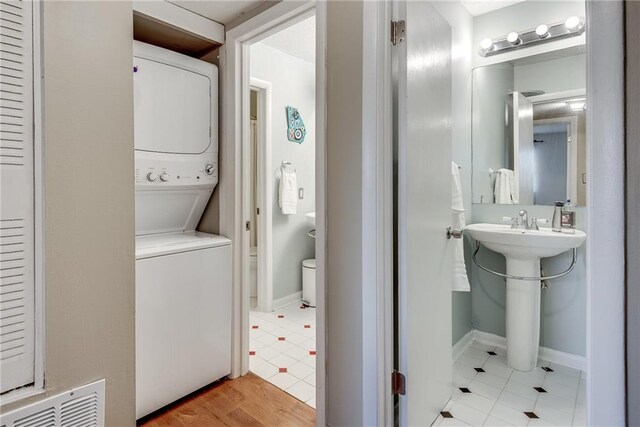 bathroom featuring stacked washer and dryer, visible vents, and baseboards