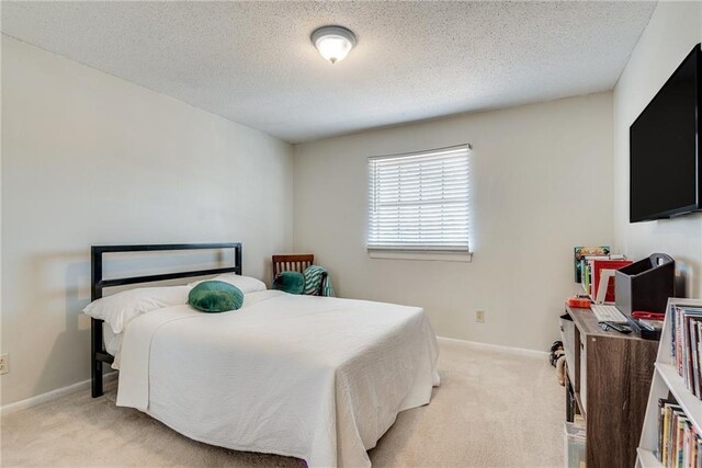 bedroom with light carpet, baseboards, and a textured ceiling