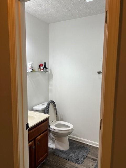 bathroom featuring vanity, toilet, a textured ceiling, and hardwood / wood-style flooring