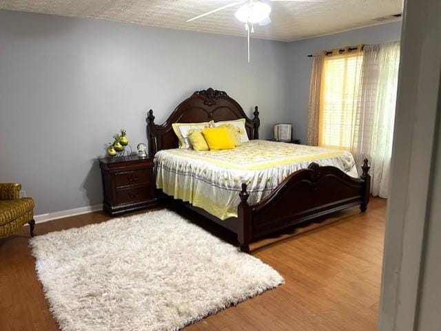 bedroom with ceiling fan, hardwood / wood-style flooring, and a textured ceiling