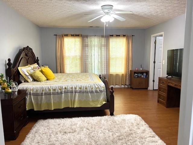 bedroom with a textured ceiling, hardwood / wood-style floors, and ceiling fan