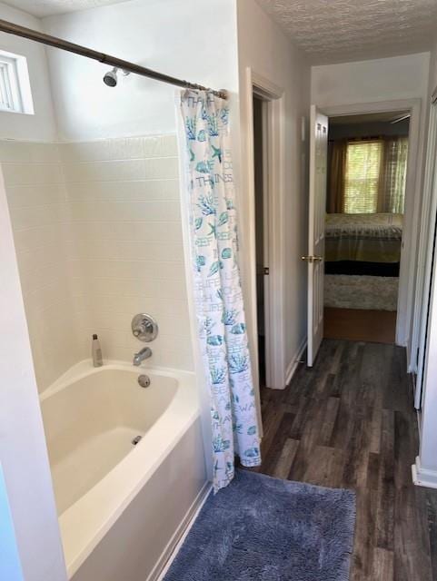 bathroom featuring hardwood / wood-style flooring, shower / bath combo with shower curtain, and a textured ceiling