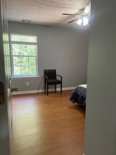 bedroom featuring ceiling fan, a textured ceiling, and hardwood / wood-style floors