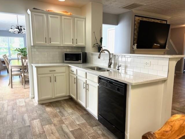 kitchen featuring black dishwasher, kitchen peninsula, light wood-type flooring, an inviting chandelier, and sink