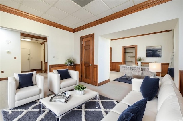 living room with ornamental molding, carpet floors, and a paneled ceiling