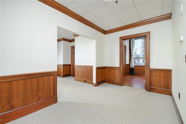 spare room with light carpet, wainscoting, and crown molding