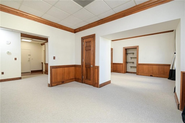 spare room with light carpet, a wainscoted wall, crown molding, and a paneled ceiling