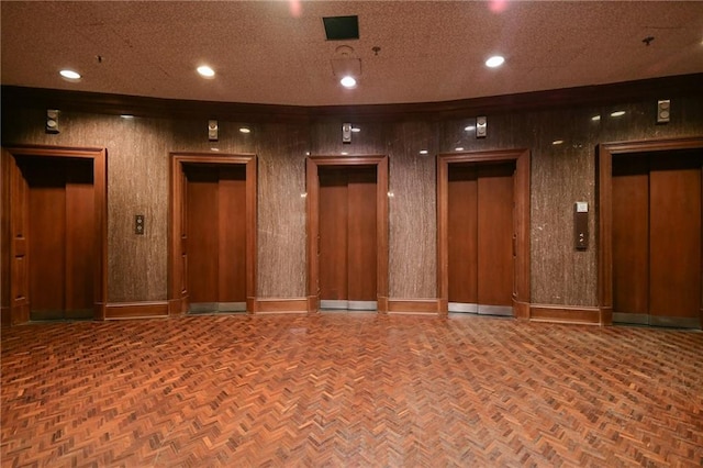 unfurnished room featuring parquet floors, wooden walls, and elevator